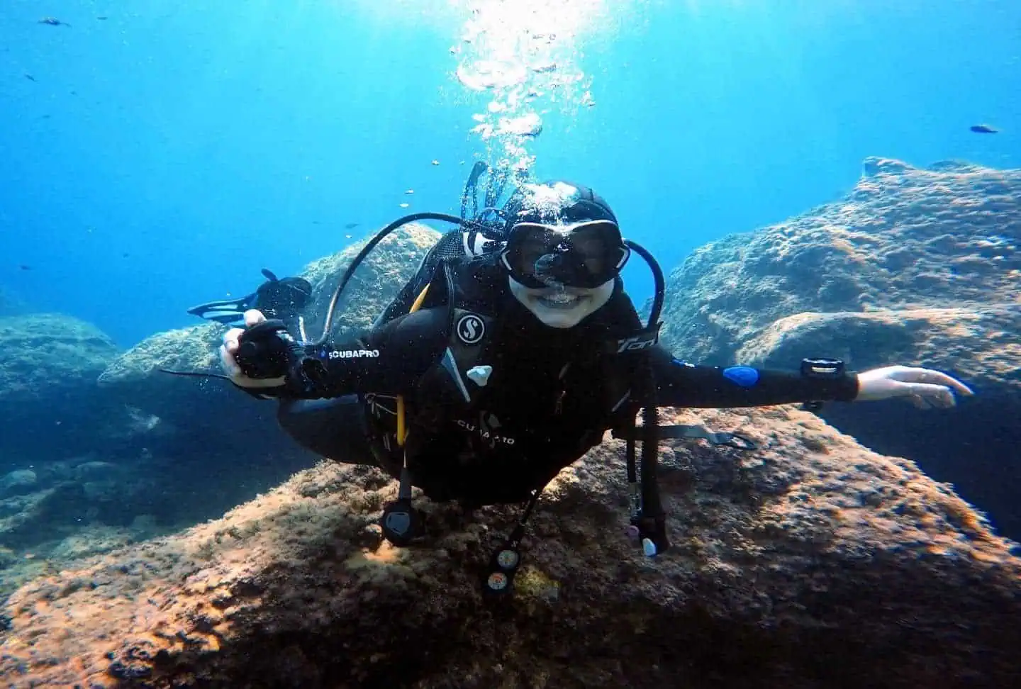 Taucher mit Neoprenanzug und Maske im kristallklaren Wasser von Taormina, Sizilien.