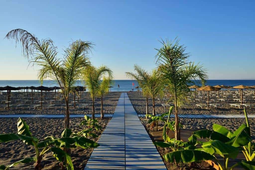 Sentiero in legno verso la spiaggia con palme e vista mare al Sea Spirit Watersports Resort.