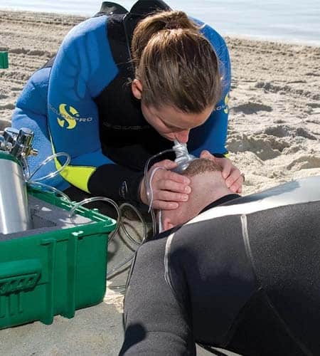 Operatore di emergenza che esegue rianimazione su un subacqueo in spiaggia.