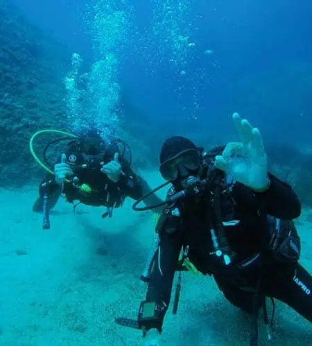 Due subacquei in immersione con attrezzatura completa in mare aperto.