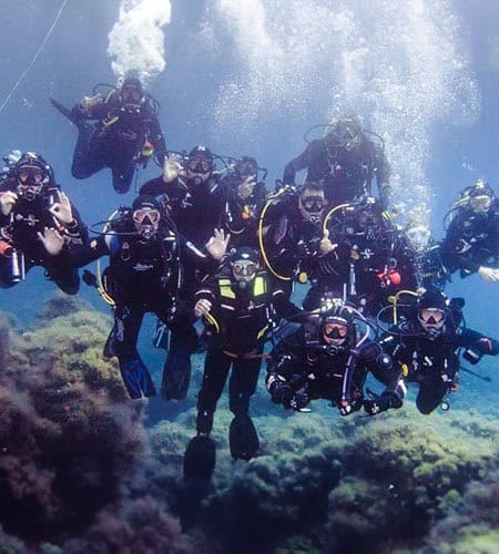 Subacquei in gruppo durante un'immersione subacquea in acque cristalline.