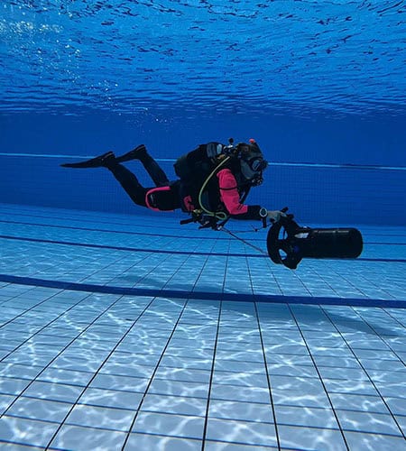 Subacqueo con attrezzatura fotografica in piscina, immersione in acque calme e cristalline.