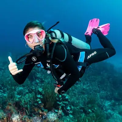 Immersione subacquea con maschera, pinne rosa e attrezzatura da diving in mare aperto.