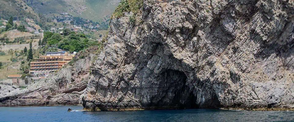 Spiaggia nascosta con grotta azzurra e acque cristalline.