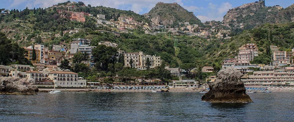 Panoramica del Scoglio delle Sirene con il borgo e le montagne sullo sfondo.
