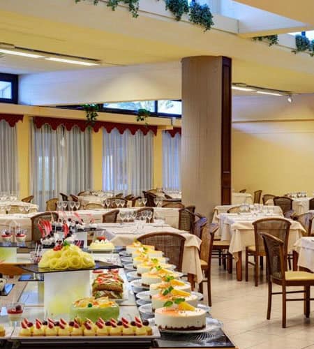 Sala da pranzo elegante con tavoli decorati e dolci per festa di compleanno.