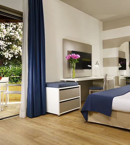 Camera che mostra una camera d'hotel moderna con fiori rosa sul tavolo.