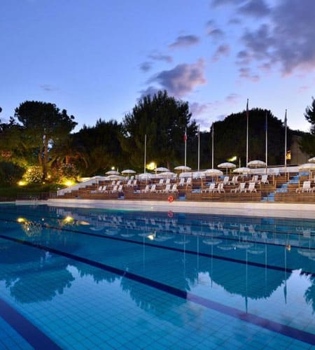 Piscina all'aperto con lettini e ombrelloni, ambiente rilassante e tranquillo al tramonto, ideale pe.