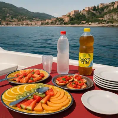 Bevande e frutta fresca su barca con vista mare e città sullo sfondo.