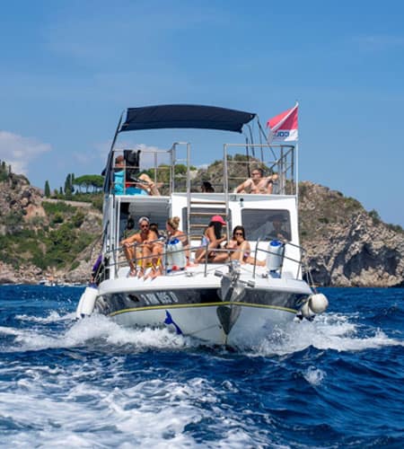 Barca a motore con persone che si rilassano in mare, godendosi il sole e il paesaggio marino.