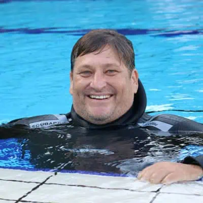 Vita marina in acqua con abbigliamento da immersione, sorridente e rilassato.