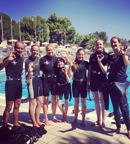Gruppo di apneisti sorridenti in piscina con attrezzatura subacquea.