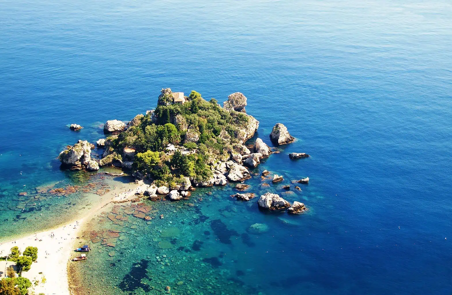 Isola di Taormina con acque limpide e scogliere rocciose, perfetta per snorkeling e escursioni marin.