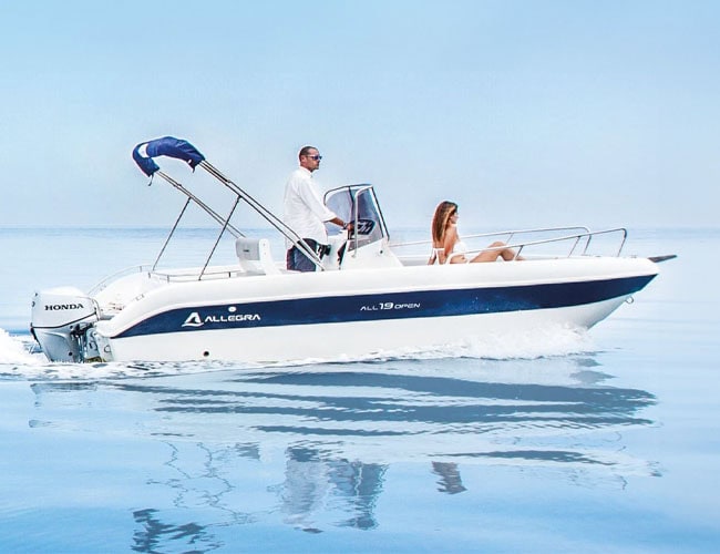 Barca a motore elegante in mare con due persone a bordo, perfetta per escursioni e relax in acqua.
