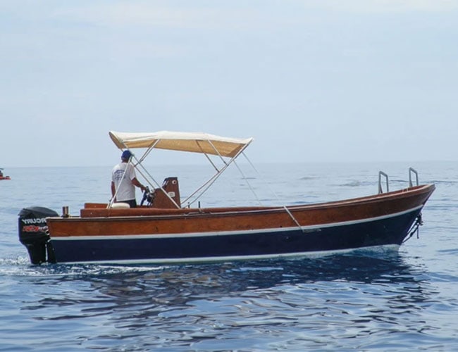 Barca a motore in mare con copertura beige, ideale per escursioni e relax in acqua.